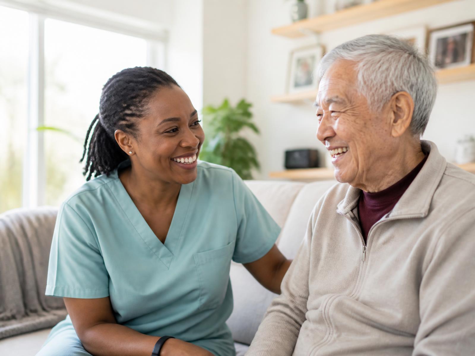 A home care aide smiling with an older client in his living room